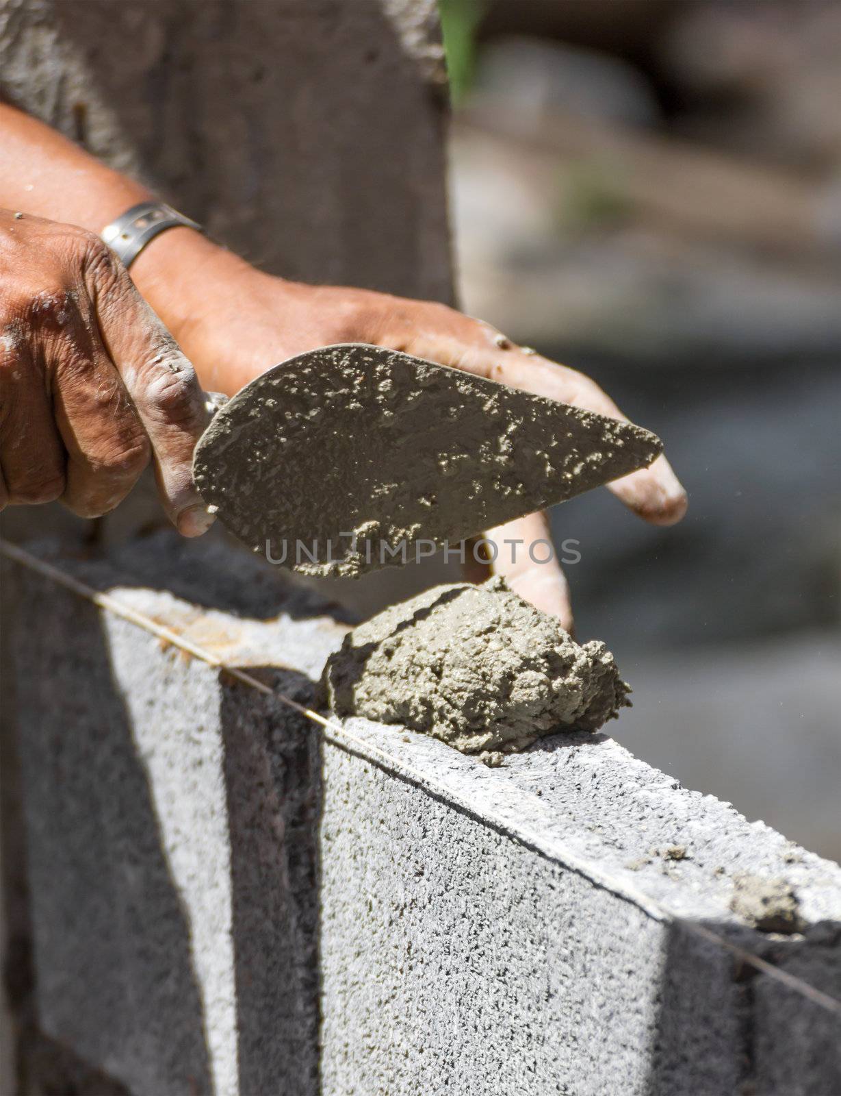 Bricklayer putting down another row of bricks in site