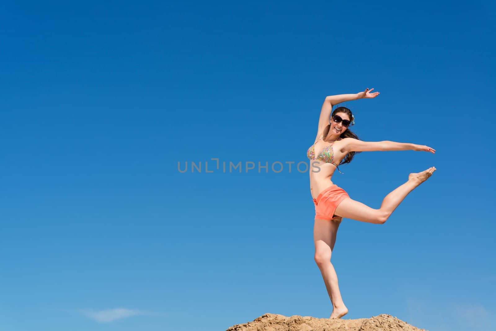 beautiful young woman jumping on a background of blue sky, having a fun time