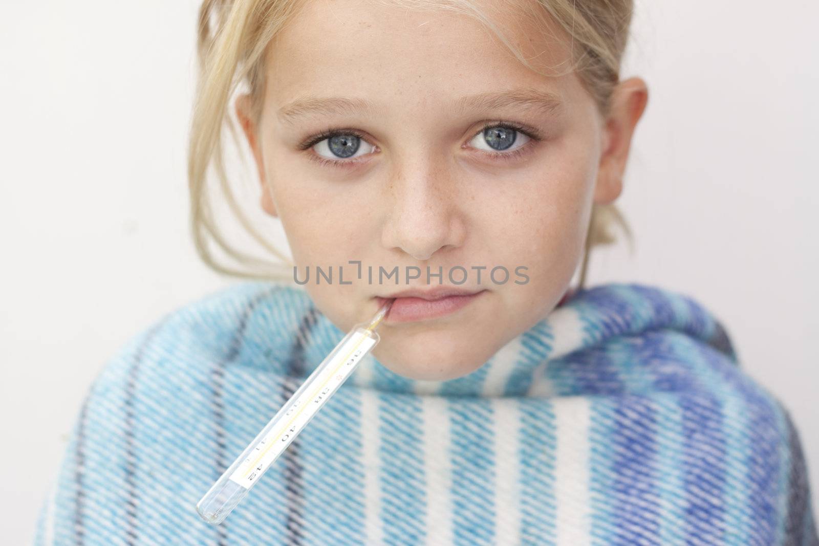 Close up of child with fever thermometer, wrapped in blanket