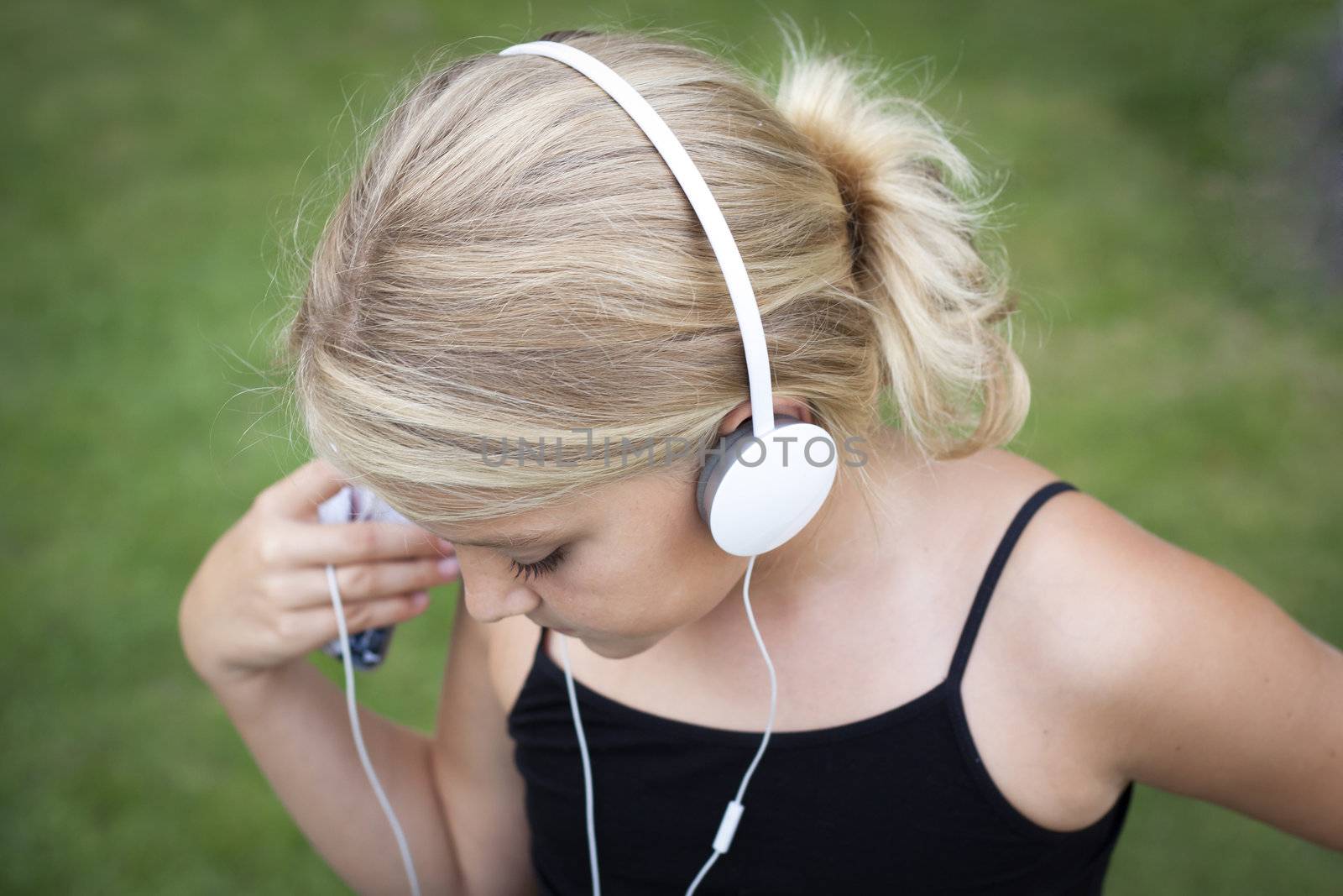 Child with headset listening to music on her smartphone. Short depth of field