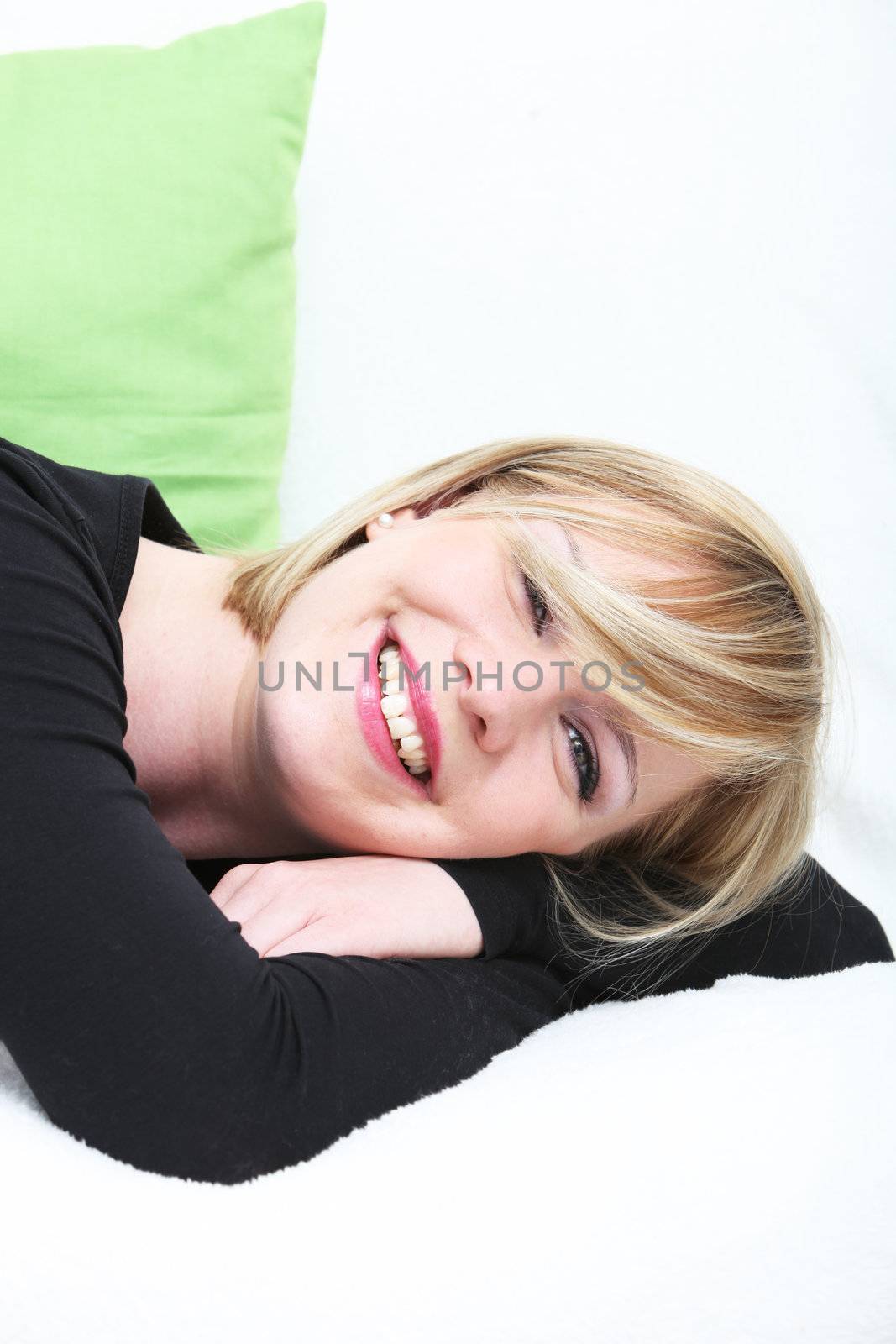 Joyful attractive woman resting lying on her stomach with her head resting on her arms