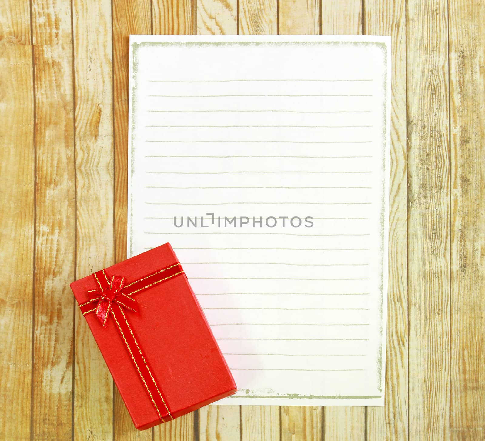 Red present box with blank note paper on wooden background 