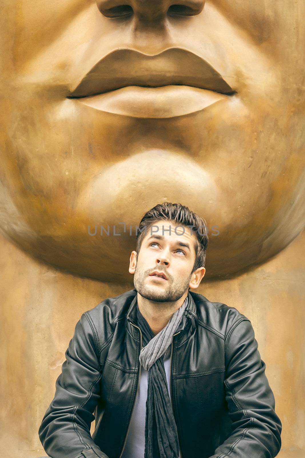 An image of a young man and a big mouth statue