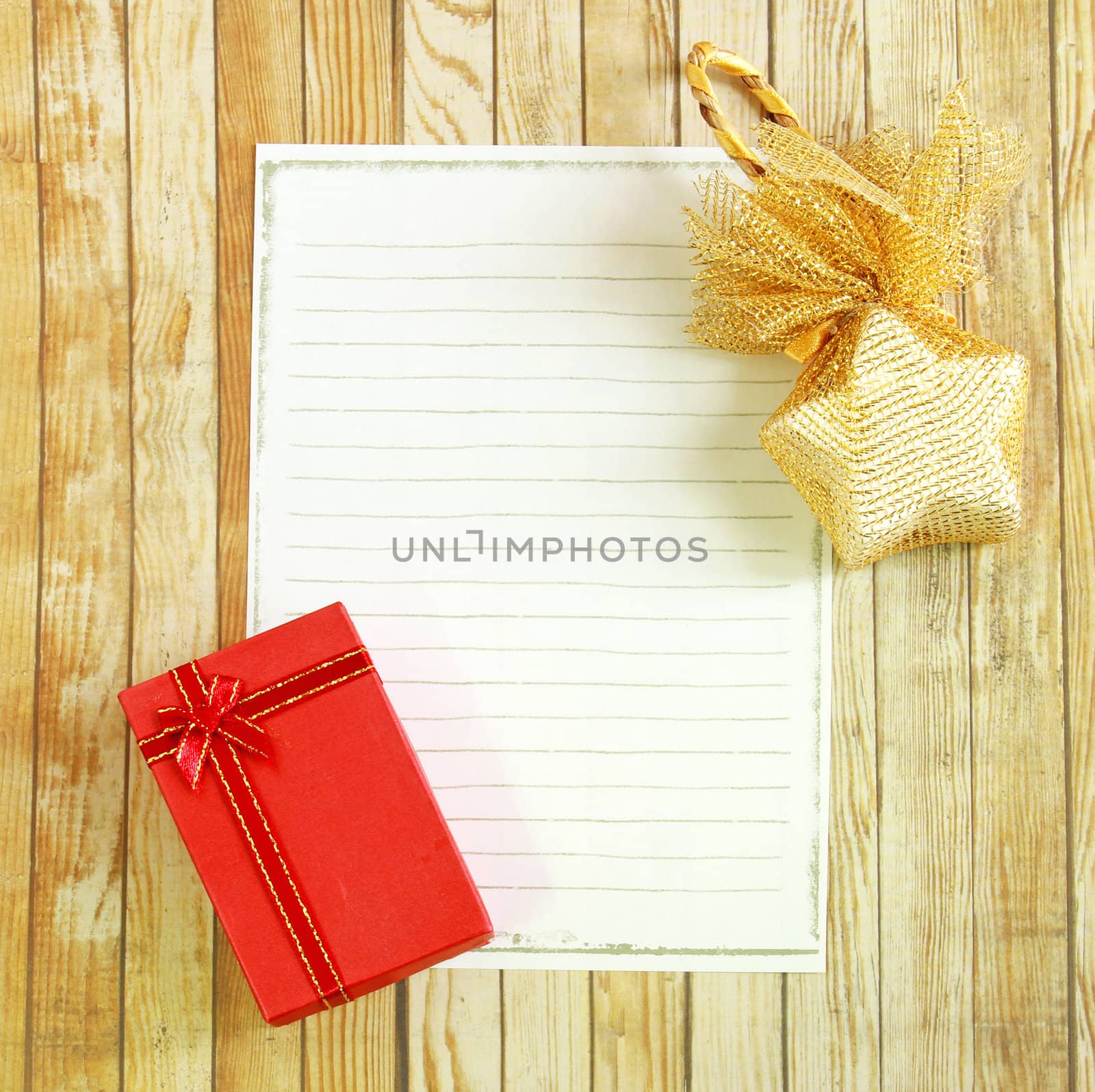 Present box and star with blank note paper on wooden background 