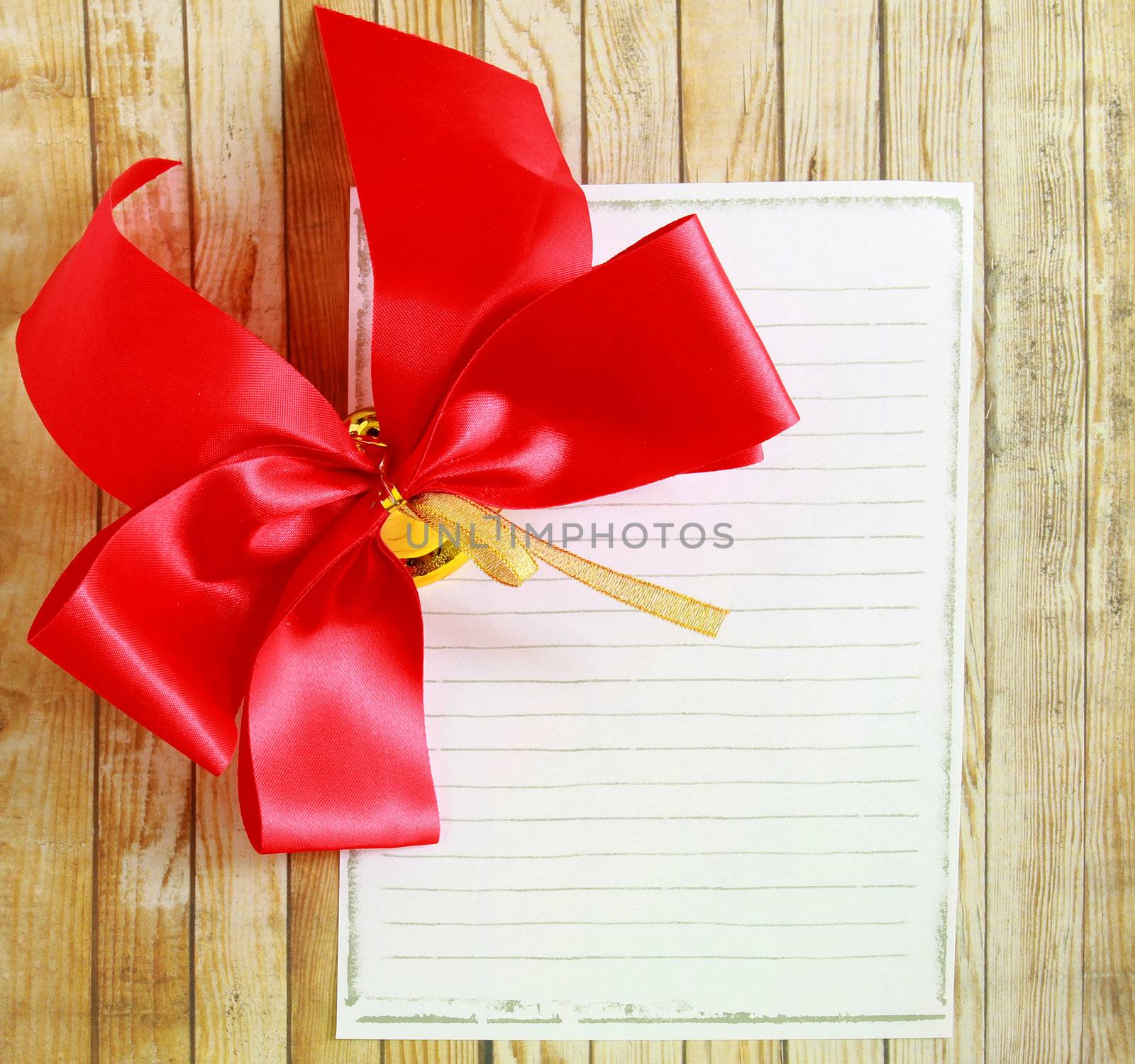 Red ribbon with blank notebook over wooden background 
