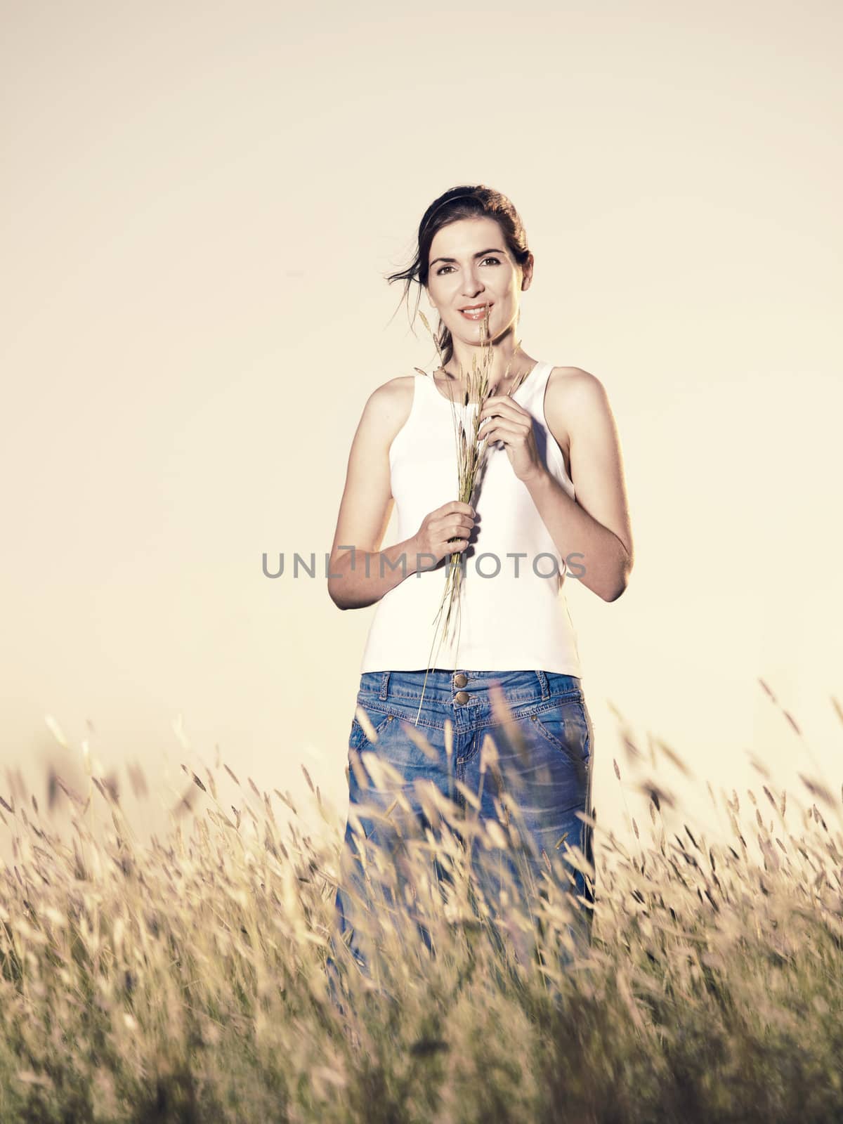 Outdoor portrait of a beautiful woman holding flowers on a summer day