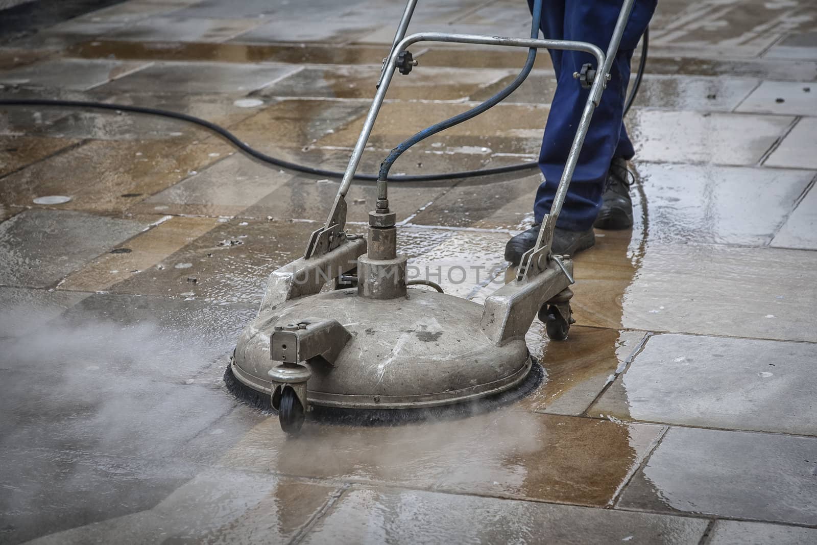 Worker cleaning a pavement in Oxford, England by steam.