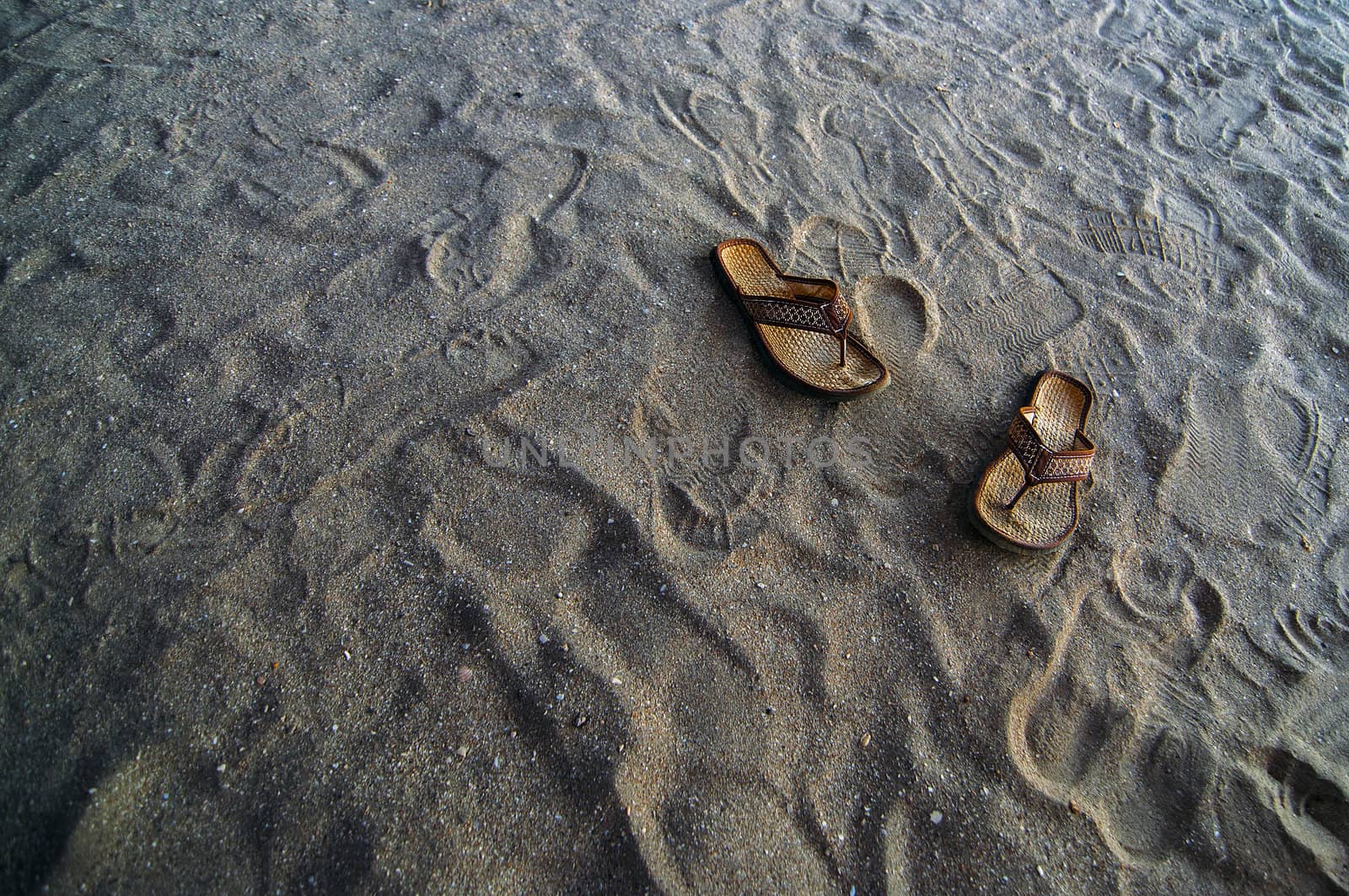 Flip flops in the sand at a beach.