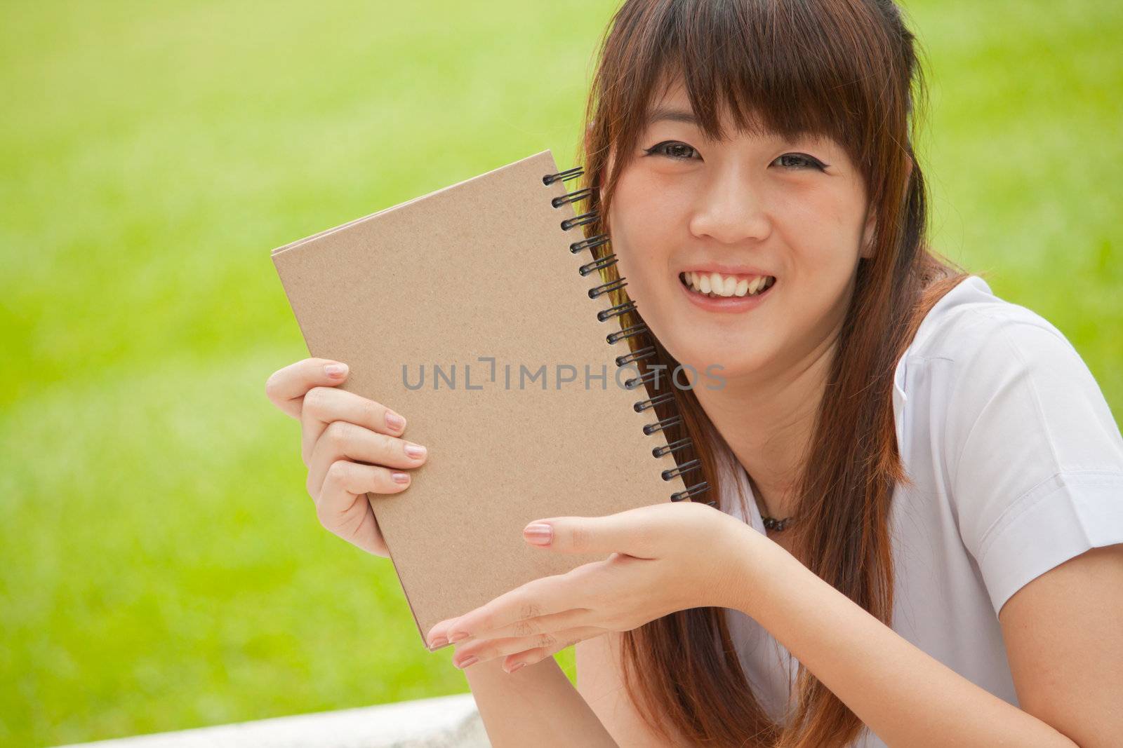 Asian girl smiling and holding her notebook