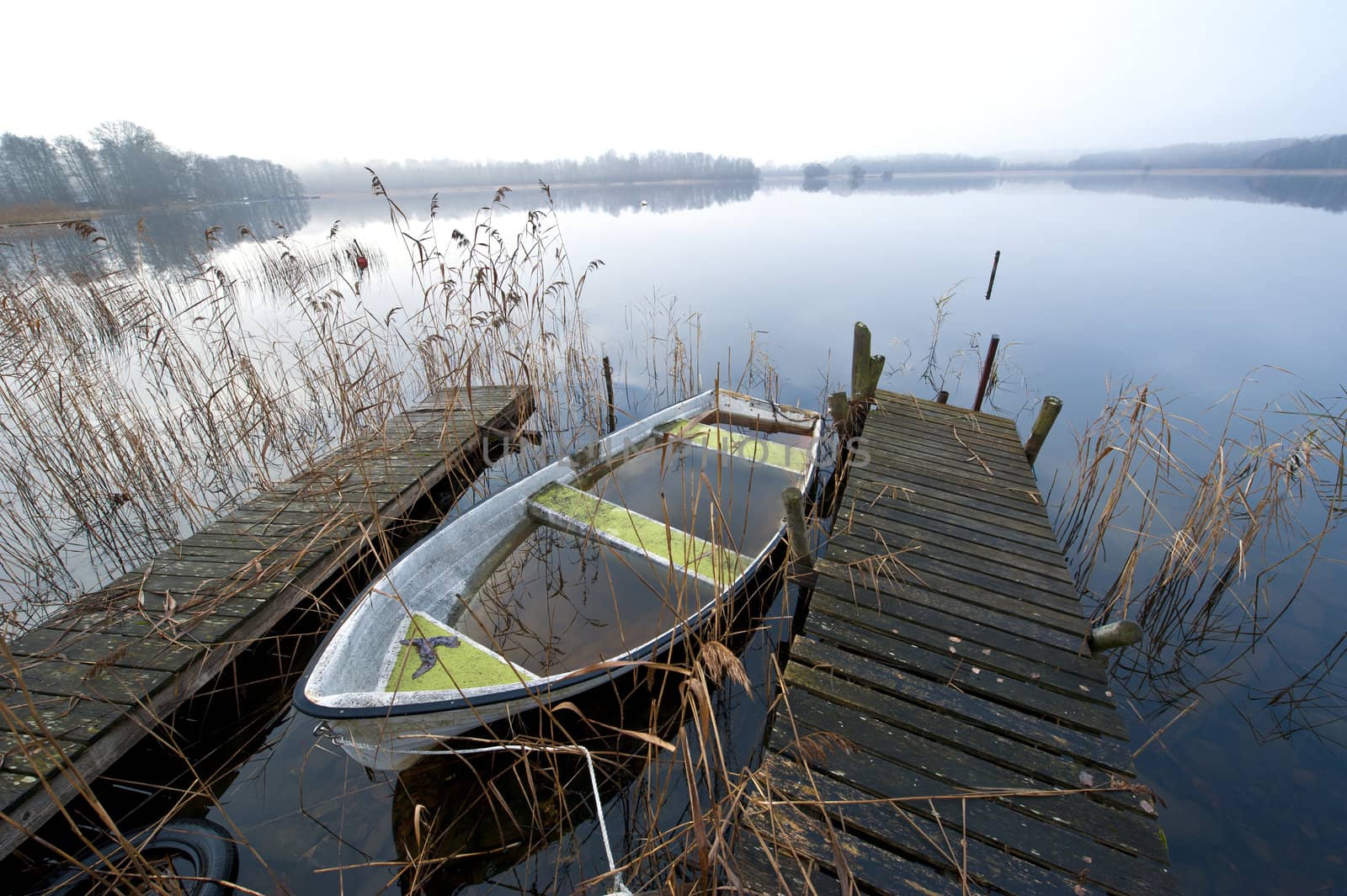 Abandoned boat at lake an misty november morning