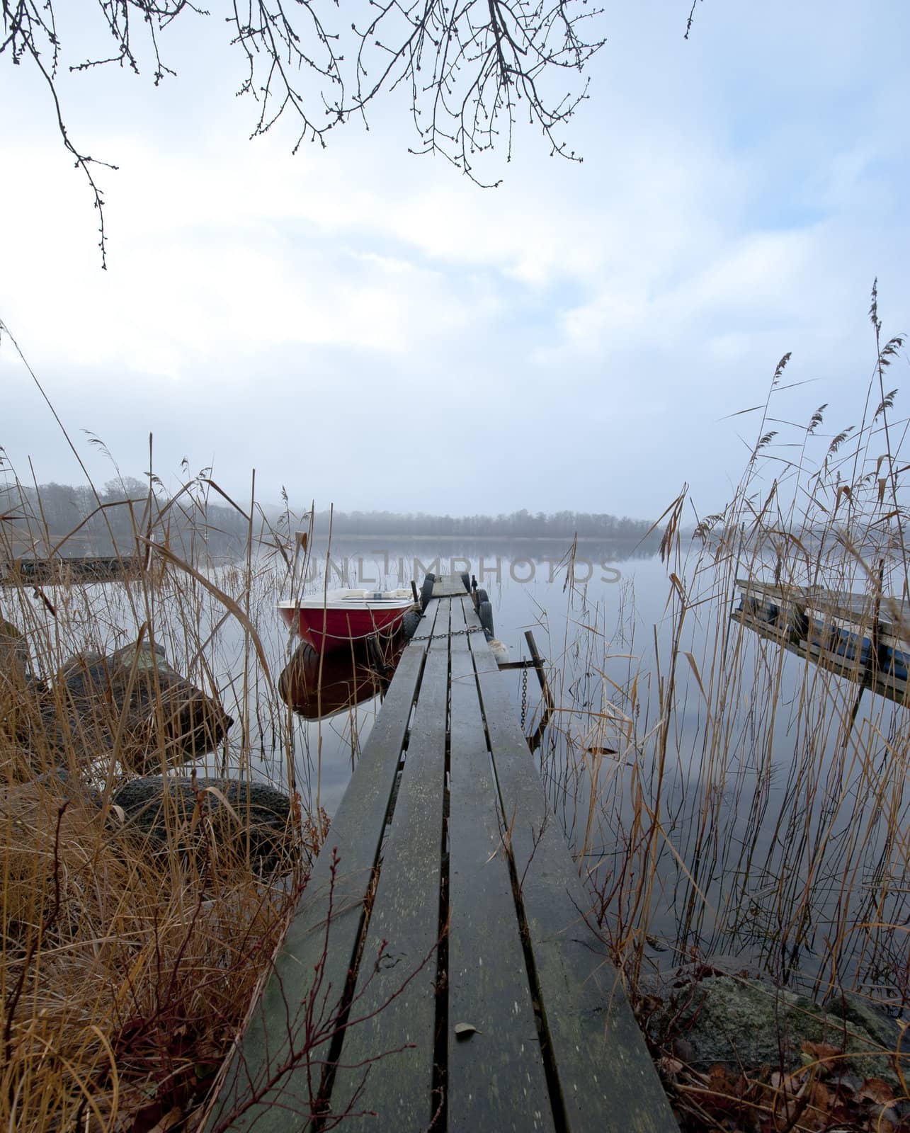 Boat moored at wodden pier in a lake an early november morning