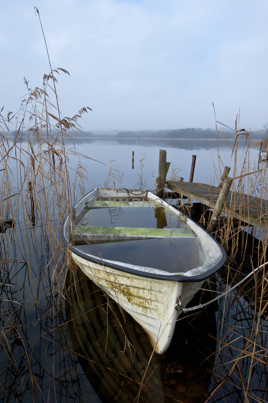 Abandoned boat at lake an misty november morning