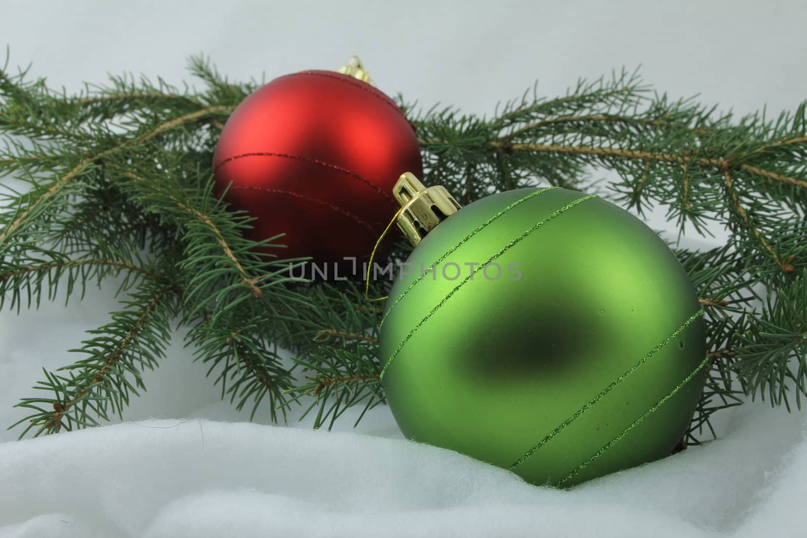 Red and green Christmas bulbs, with needles on white background
