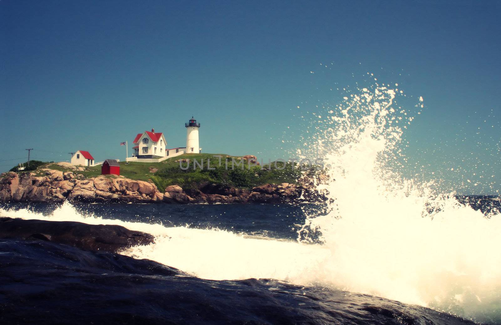 Waves crashing on rocks in front of the Nubble Lighthouse