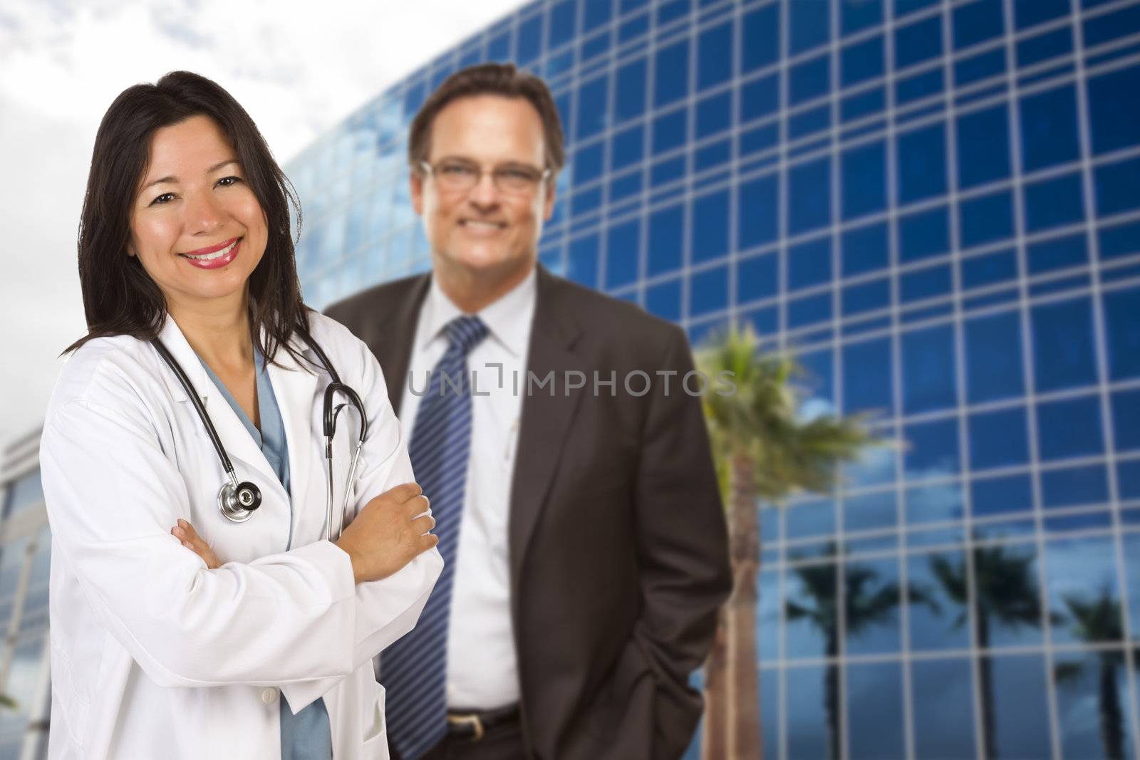 Attractive Hispanic Doctor or Nurse and Businessman in Front of Corporate Building.