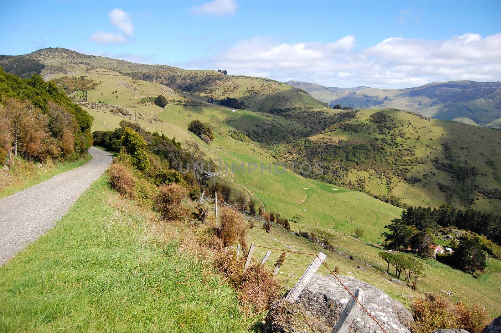 Gravel road goes downhill to rural valley, Banks Peninsula, New Zealand