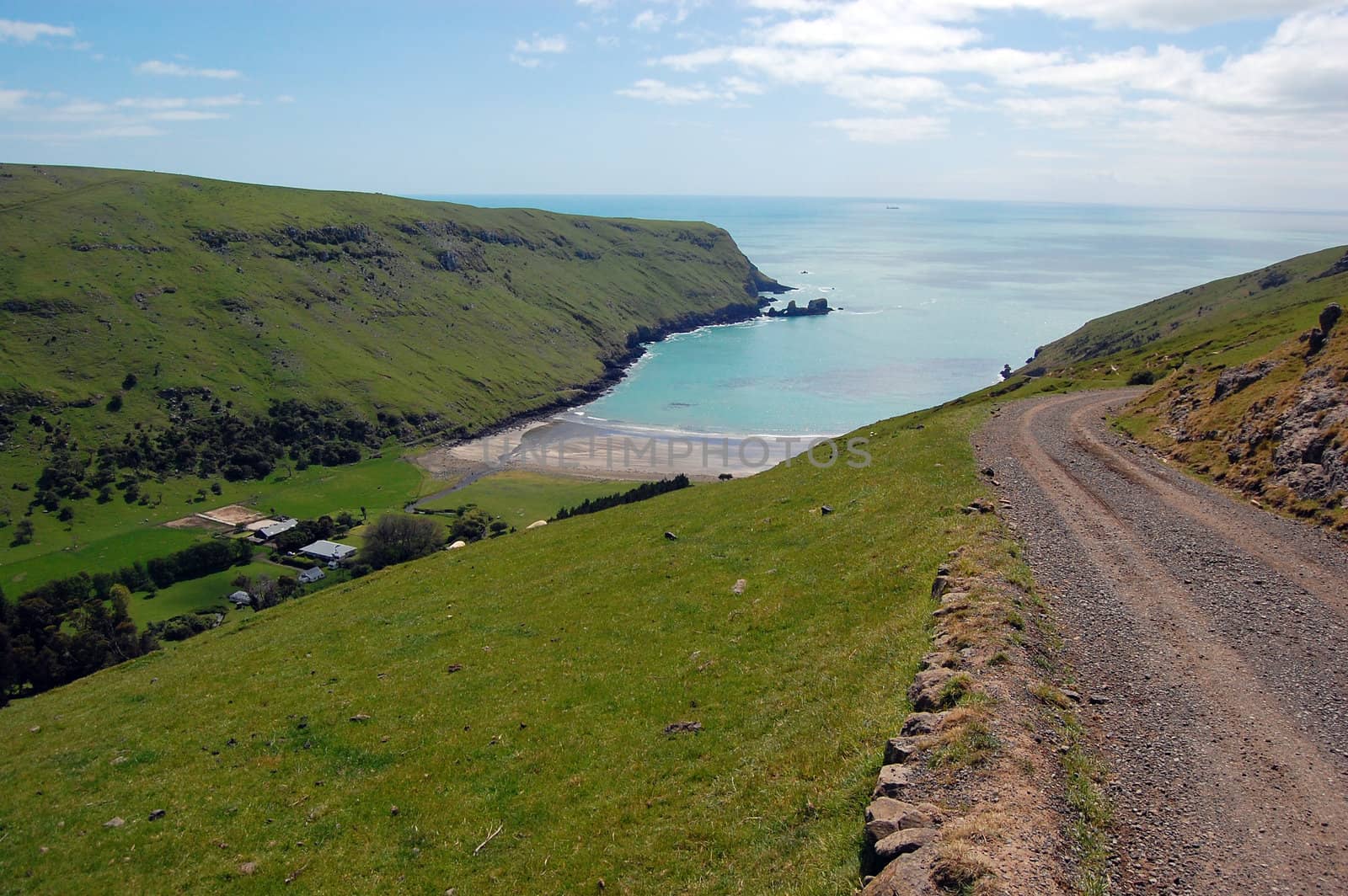 Gravel road goes downhill to rural valley, Banks Peninsula, New Zealand