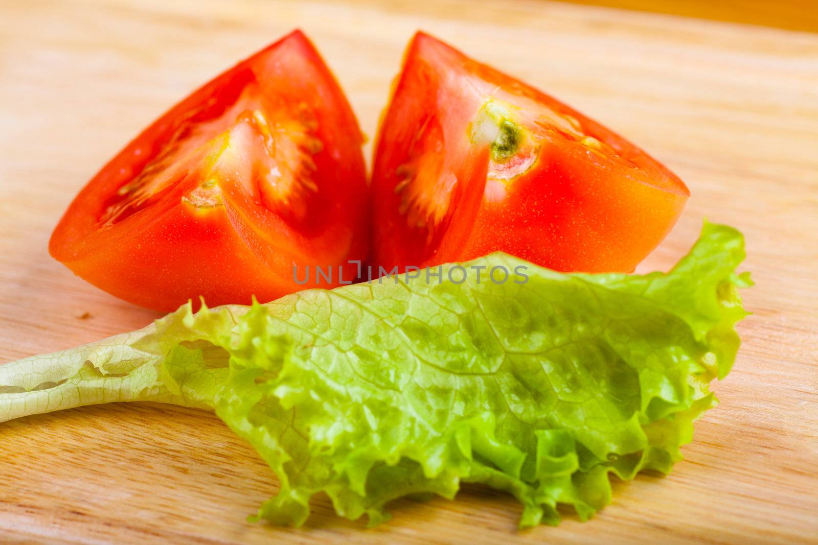 Cutted tomato and salad leaf on a wooden table