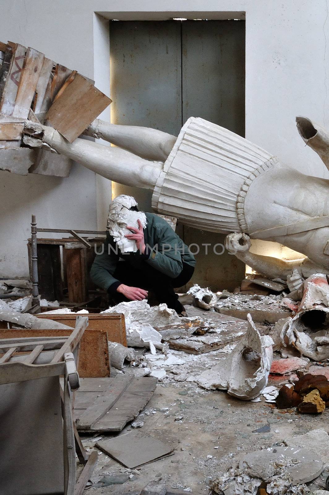 Obscured figure among ruins broken statues and debris in post apocalyptic setting.