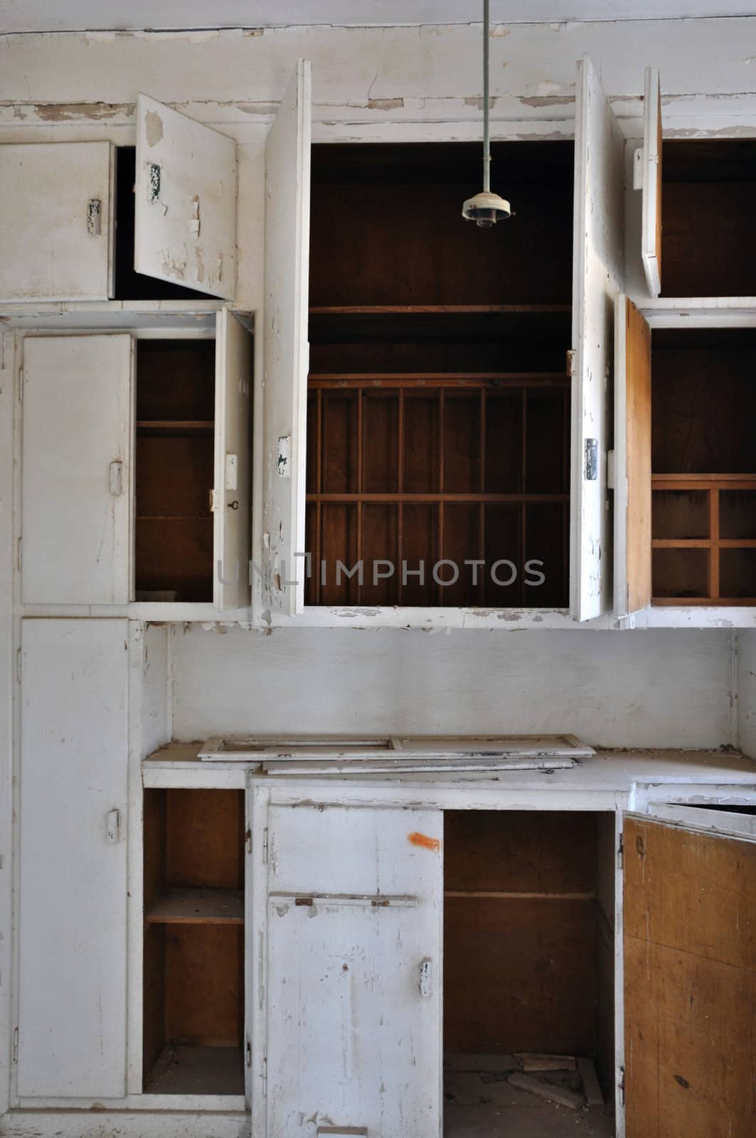 Empty cupboards in the dusty kitchen of an abandoned house.