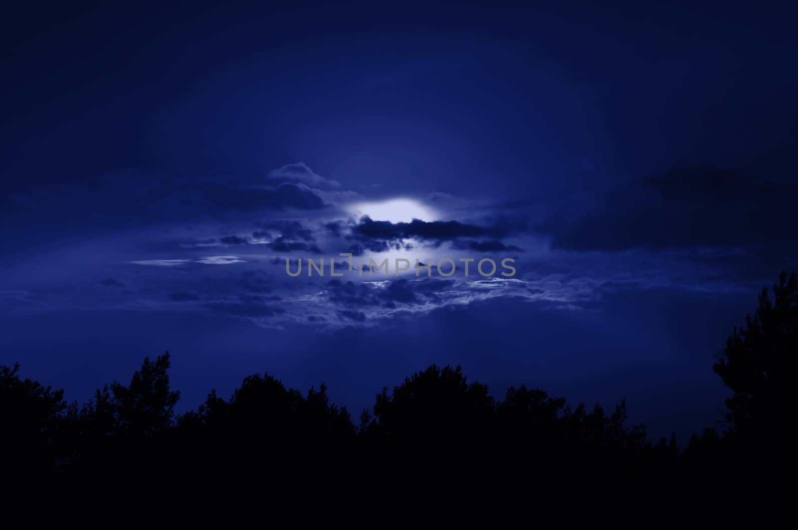 Full moon obscured by clouds. Night sky moonlight nature background.