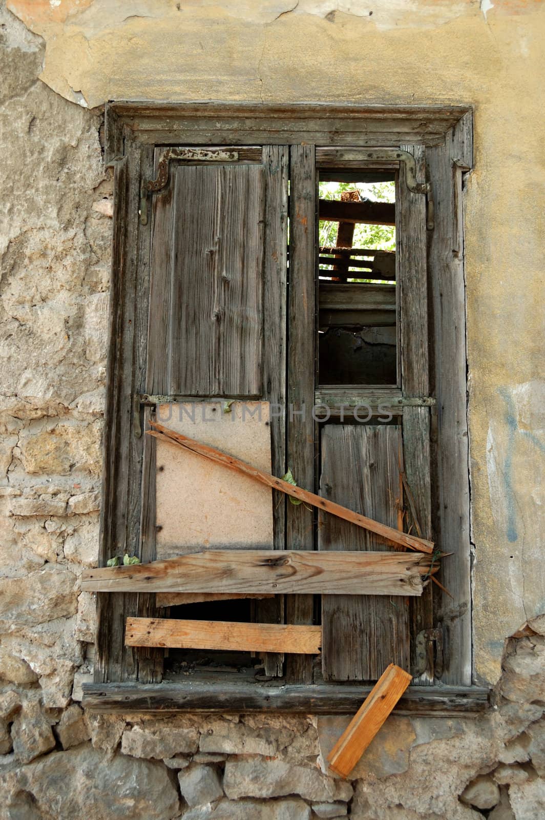 Boarded up old window shutter and crumbling wall of abandoned house.