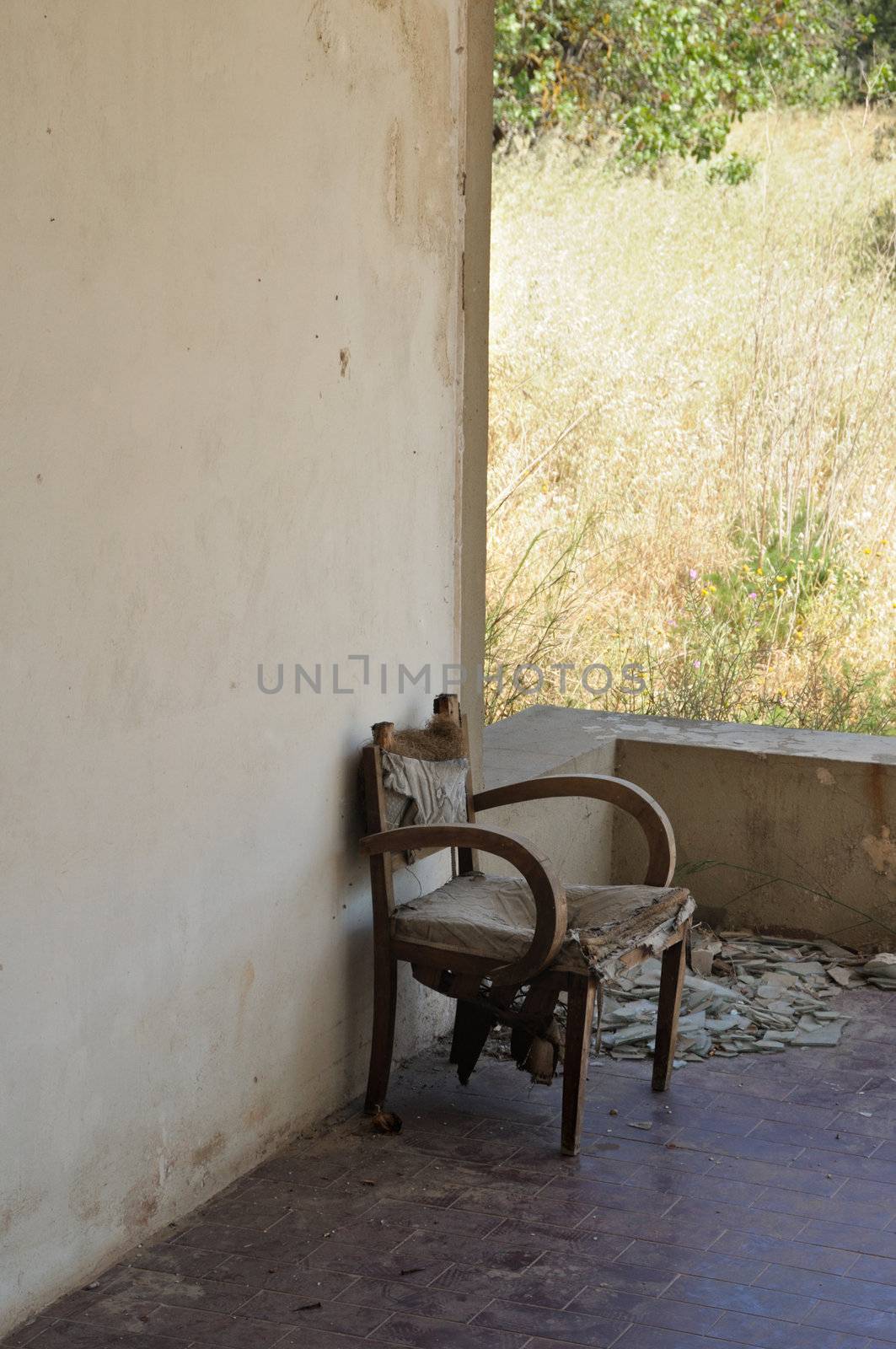 Old armchair and broken glass on the porch of an abandoned rural house.
