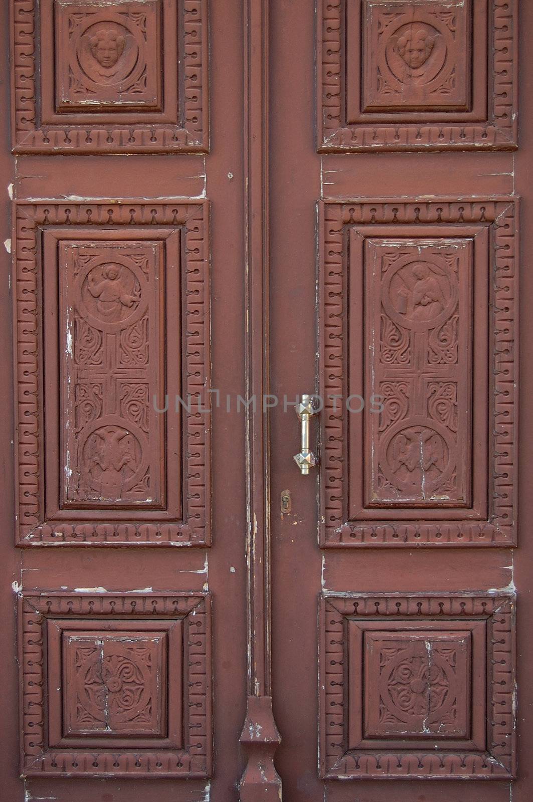 Wooden church door with carved religious symbols. Angels and cross motif.