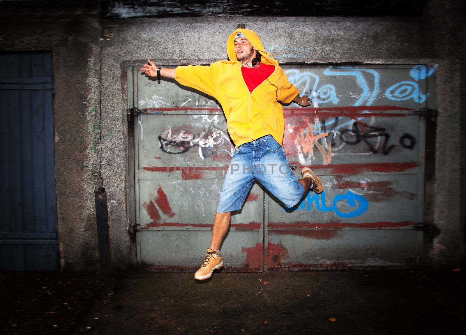 Young man jumping on grunge wall by photocreo