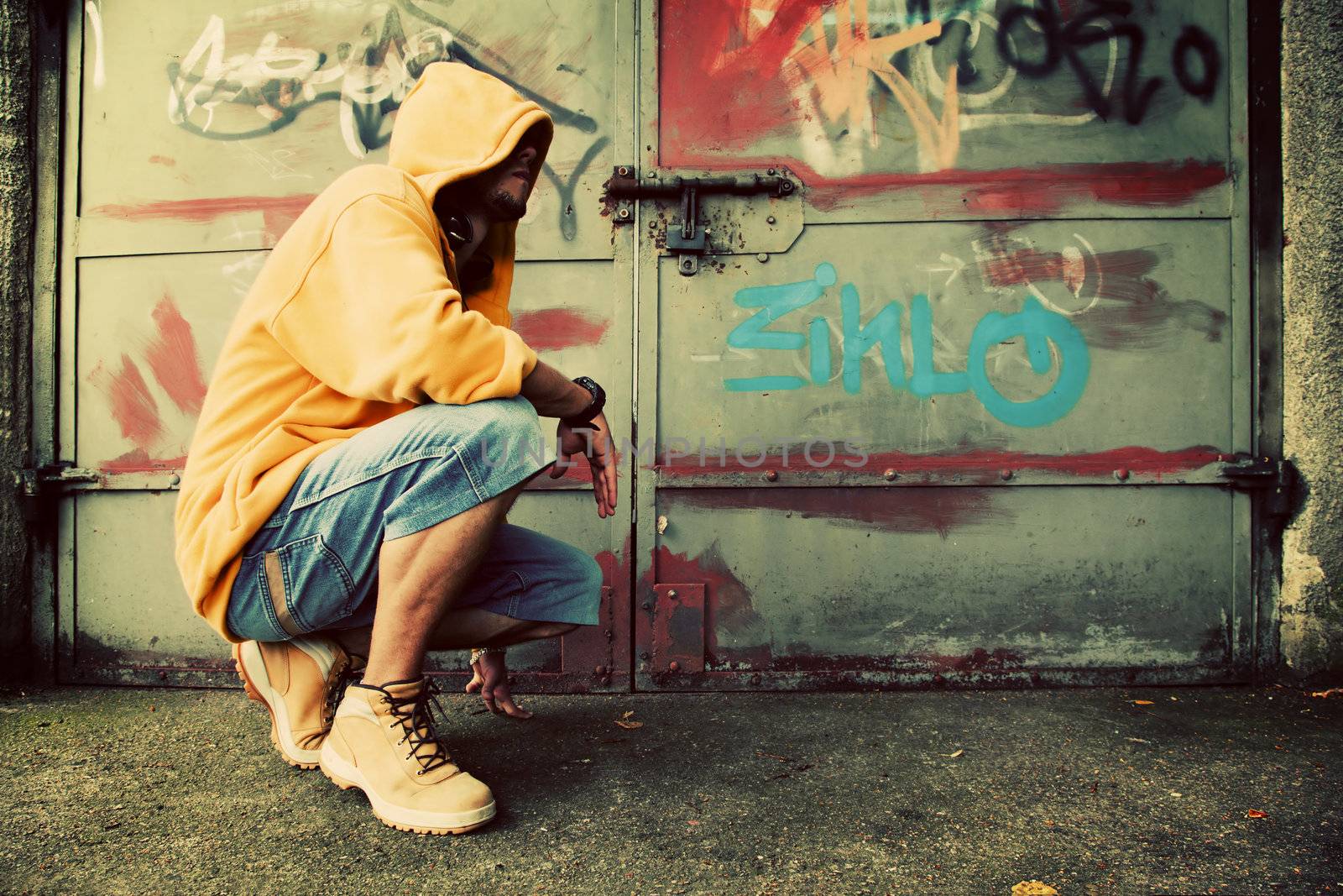 Young man portrait in hooded sweatshirt / jumper on grunge graffiti wall