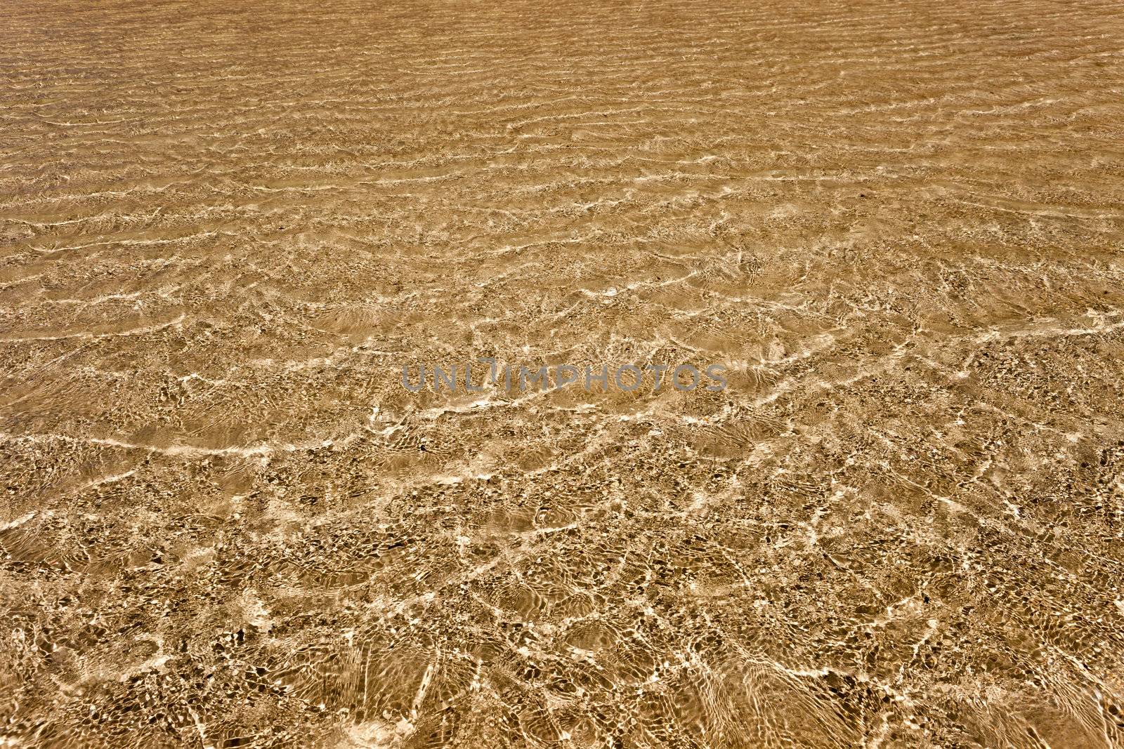 Transparent water above the golden sand