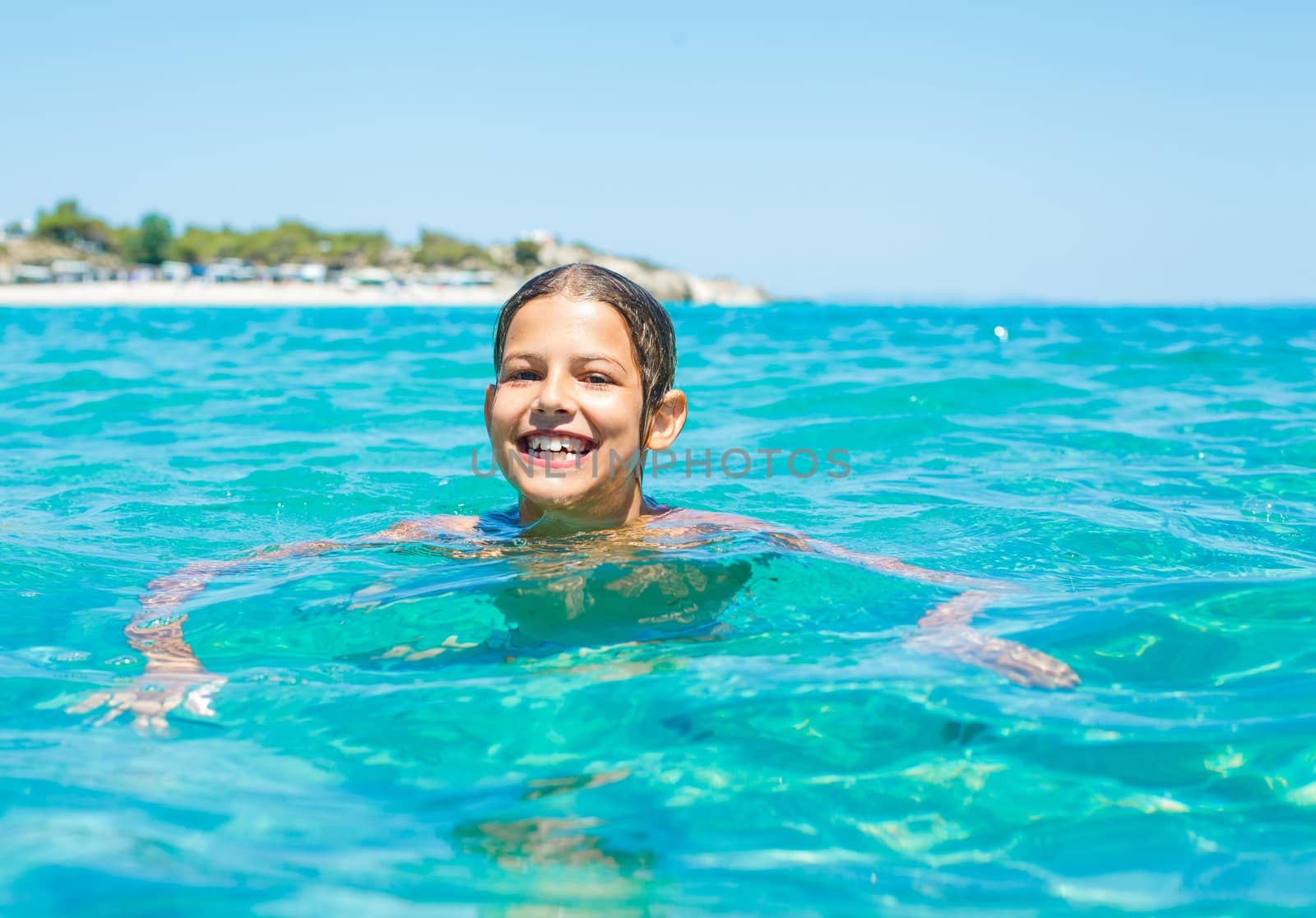Young girl playing and swimming in the transparent sea