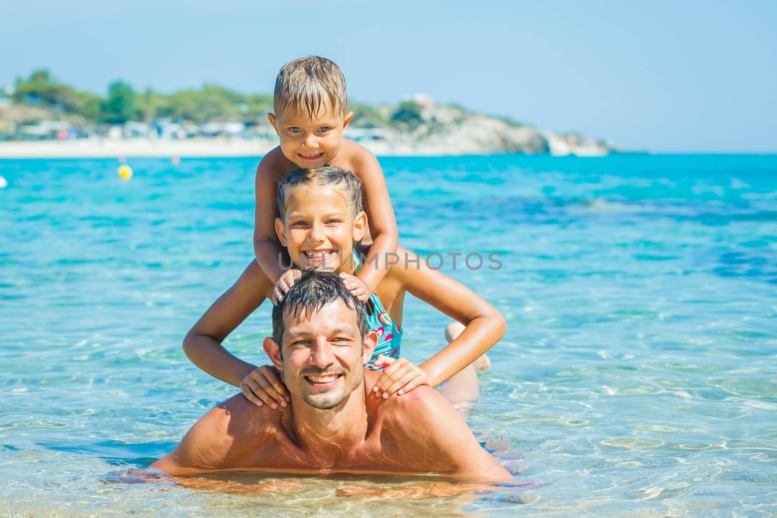 Family - father with his kids have fun and swimming in the transparent sea