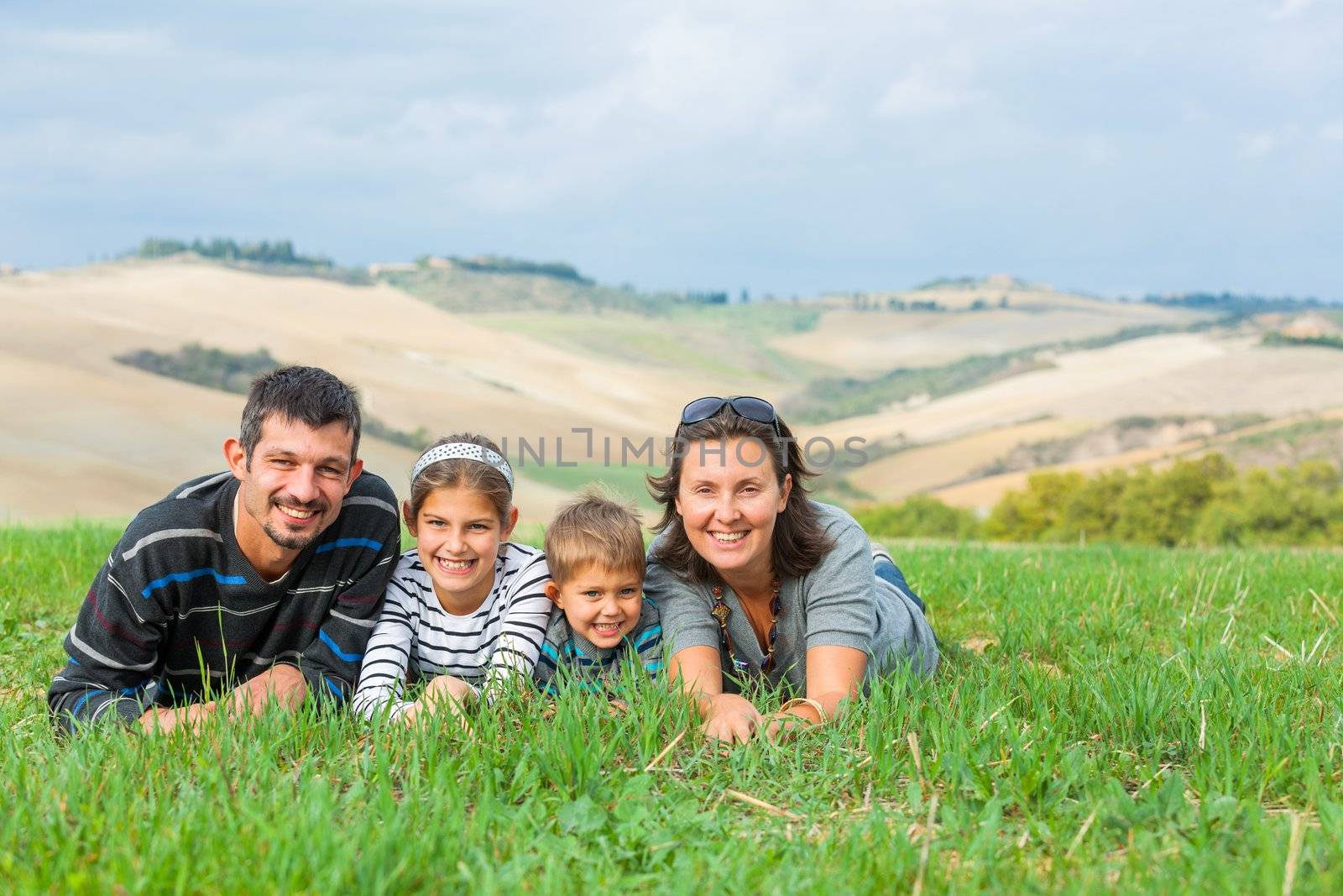 Happy family having fun on vacations in Tuscan against cypress alley background