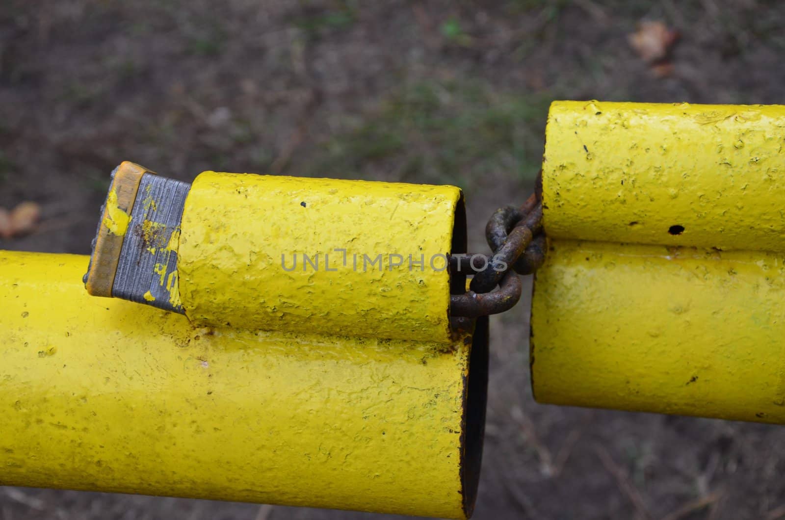 An old yellow gate secured with a pad lock and shown up close,