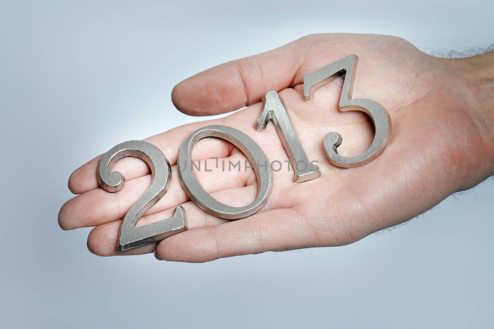 Man holding metallic numbersfor year 2013 in his hand.