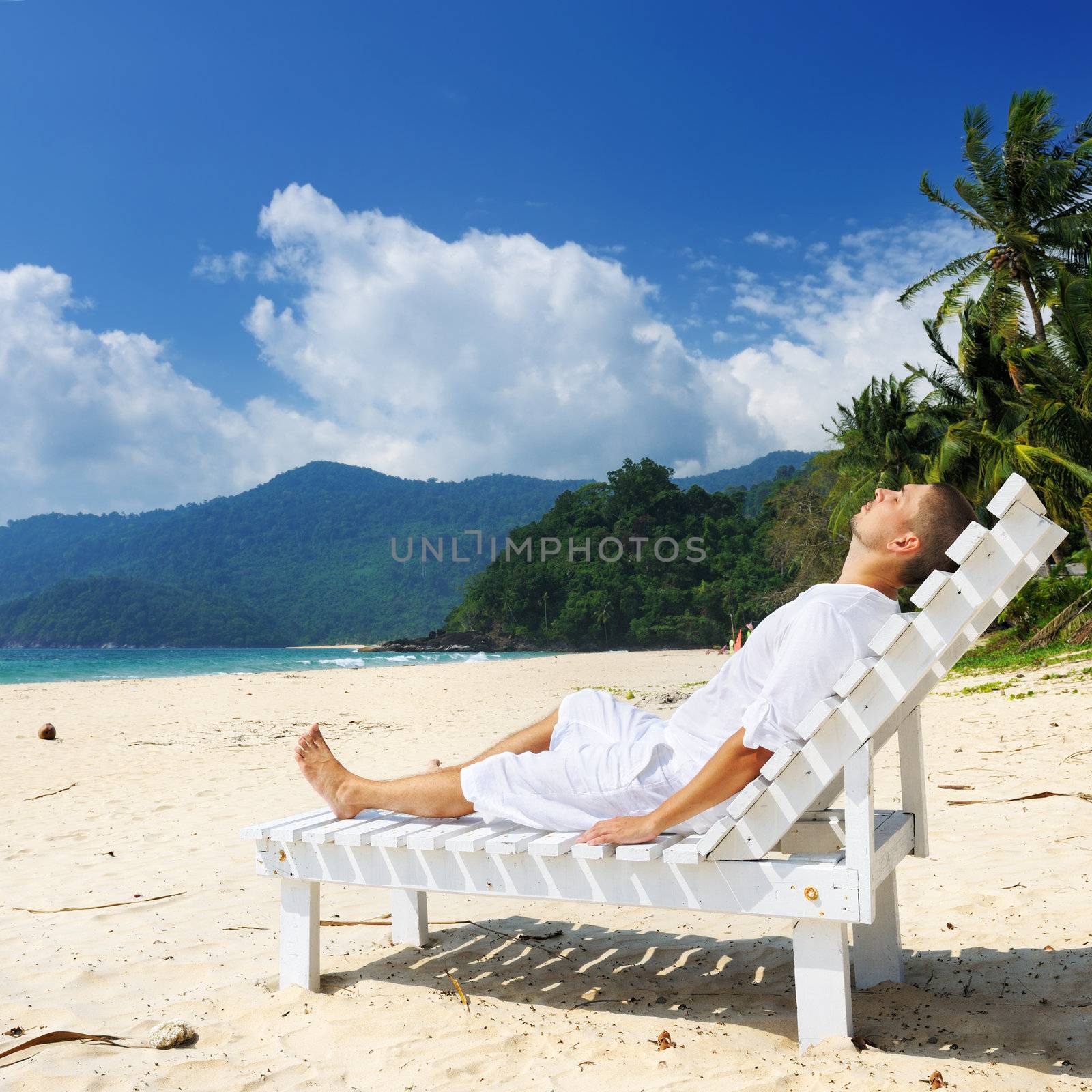 Man in white relaxing on a tropical beach