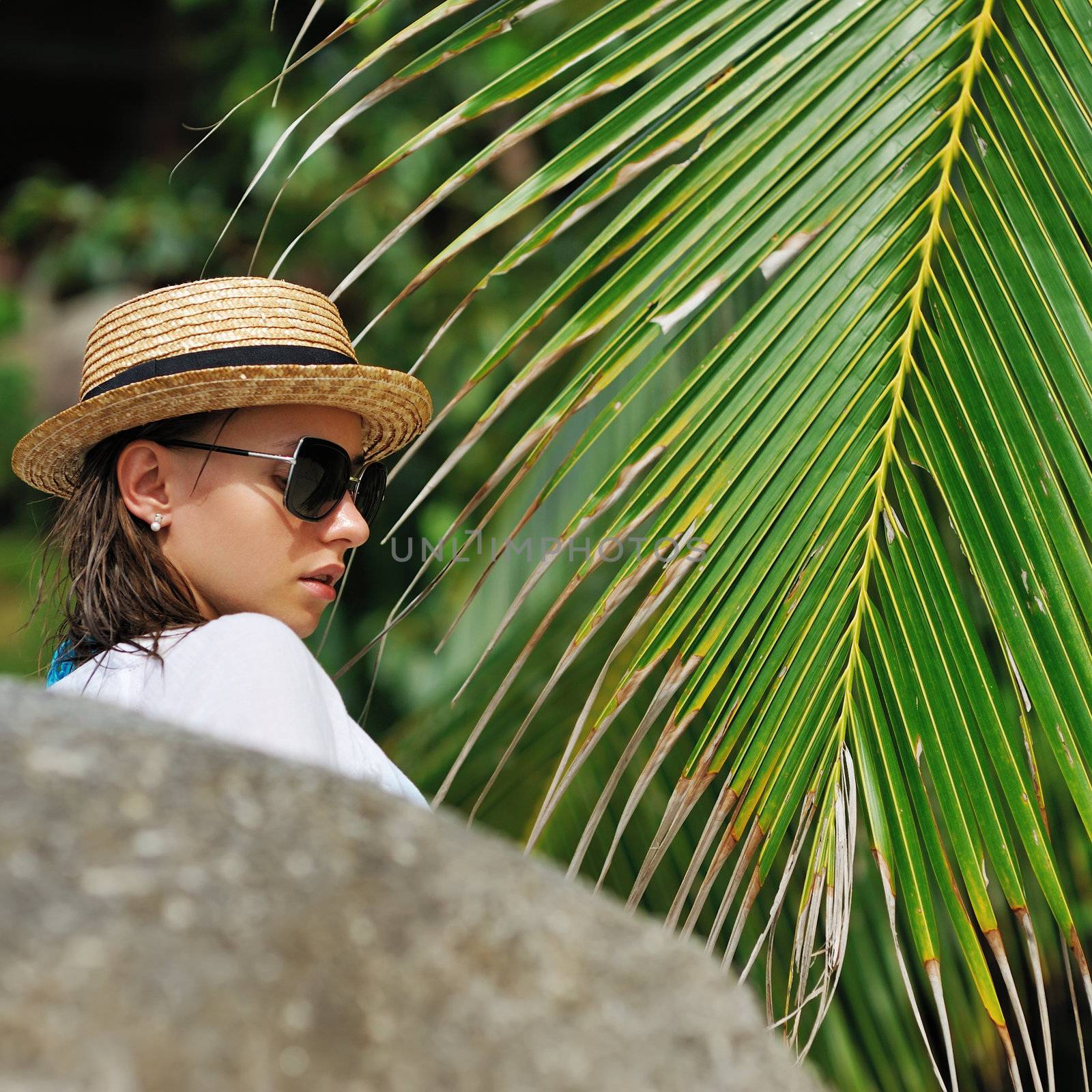 Woman in sunglasses near palm tree wearing hat