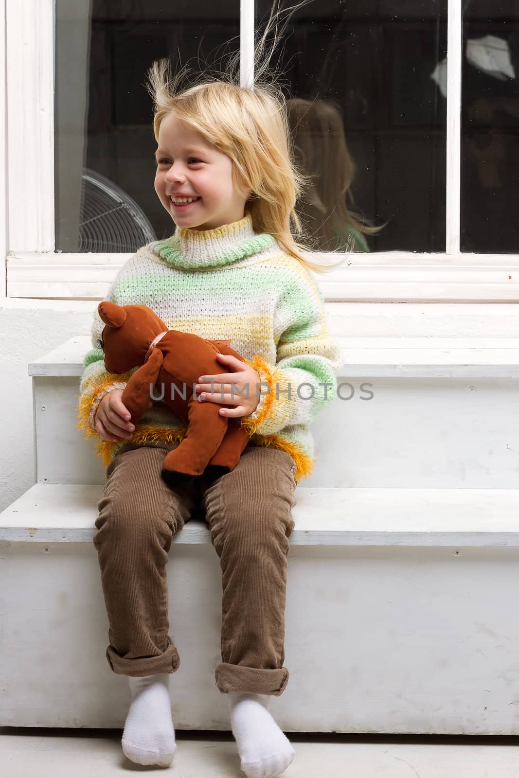  little girl with a toy in the hands with flowing hair from the fan