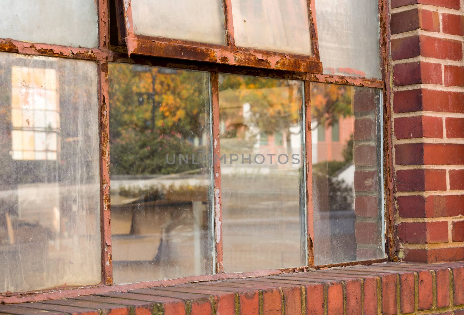 Detail of rusting window frame in brick warehouse or factory reflecting fall colors