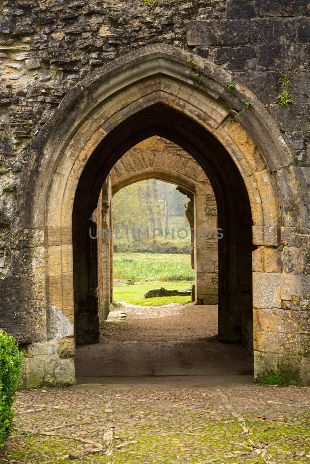 Entrance arches of Minster Lovell in Cotswold village with graveyard