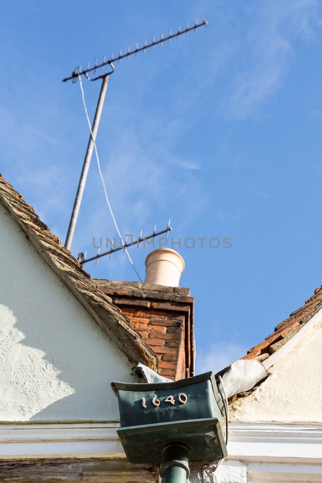 Contrast of old and new with TV aerial and old lead gutter drainpipe on roof of house