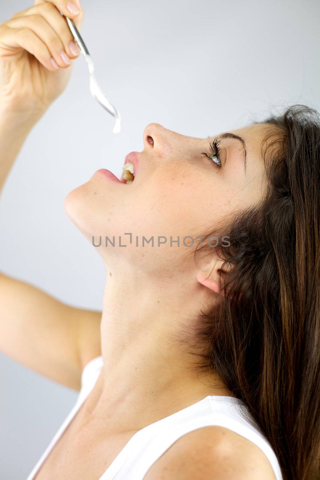 Drops of yogurt fall in mouth of beautiful woman by fmarsicano