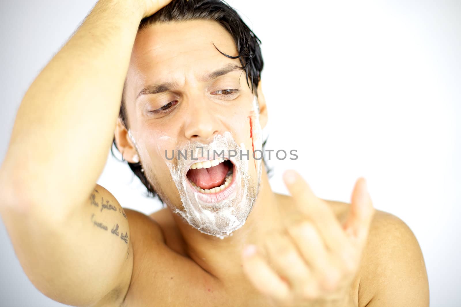 Handsome man shouting with blood on his face after shaving by fmarsicano