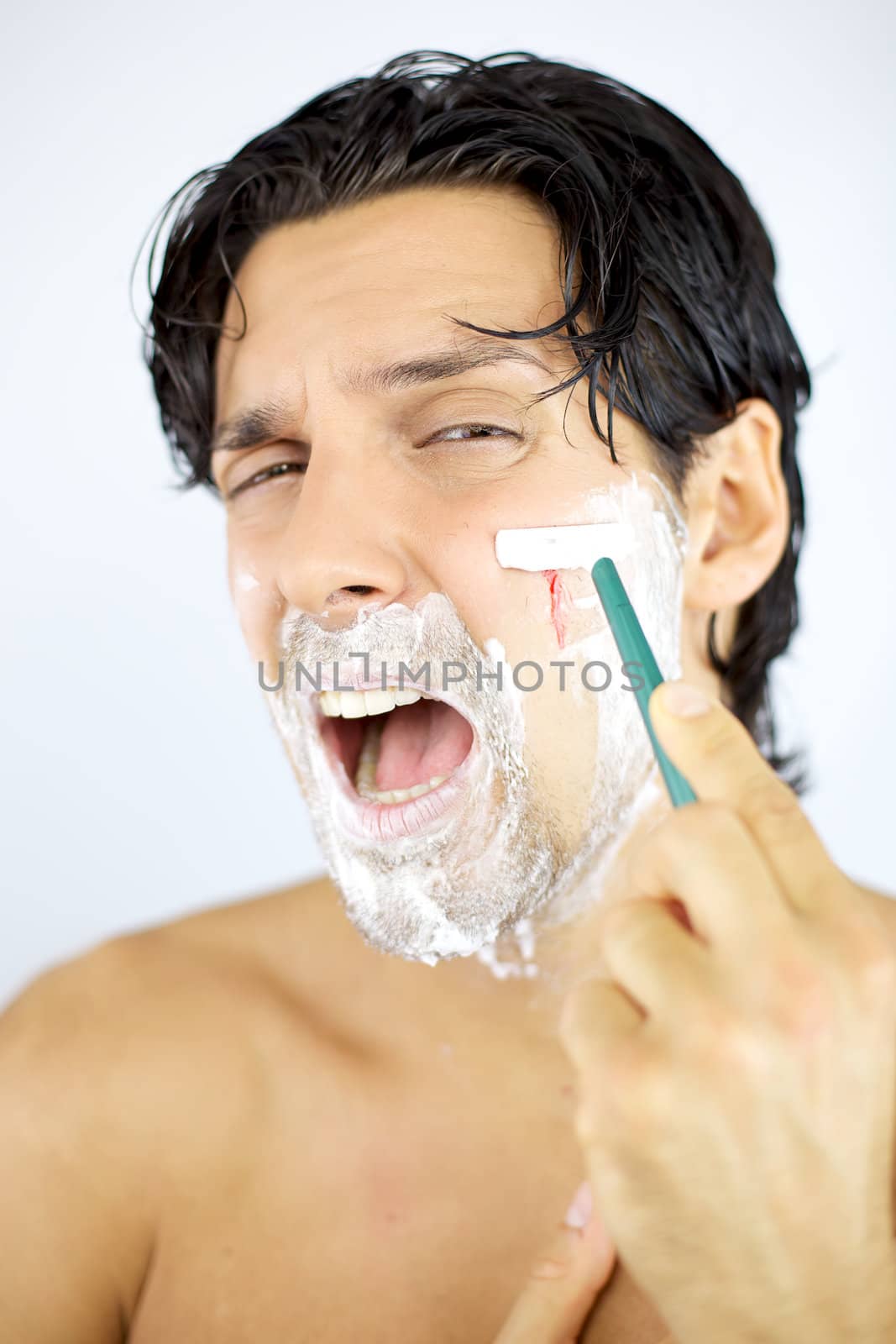 Man bleeding while shaving face with blade scared