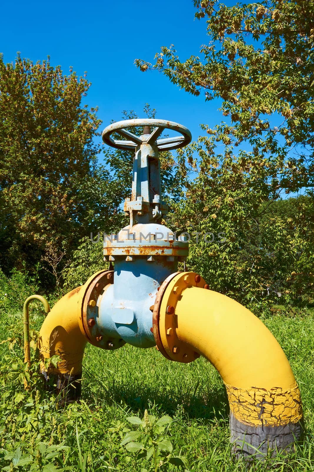 Large bent metal gas pipe with a valve on a green lawn