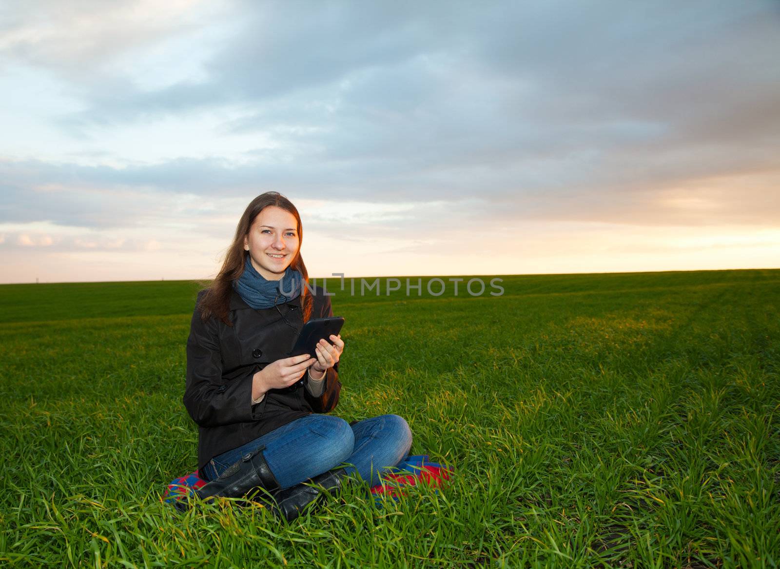 Teen girl reading electronic book outdoors by AndreyKr
