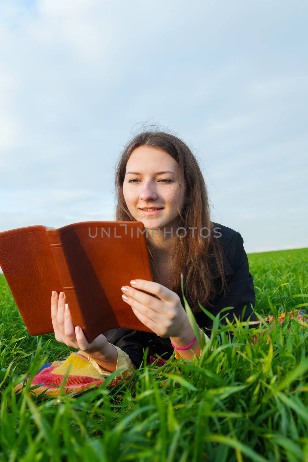 Teen girl reading the Bible outdoors at sunset time