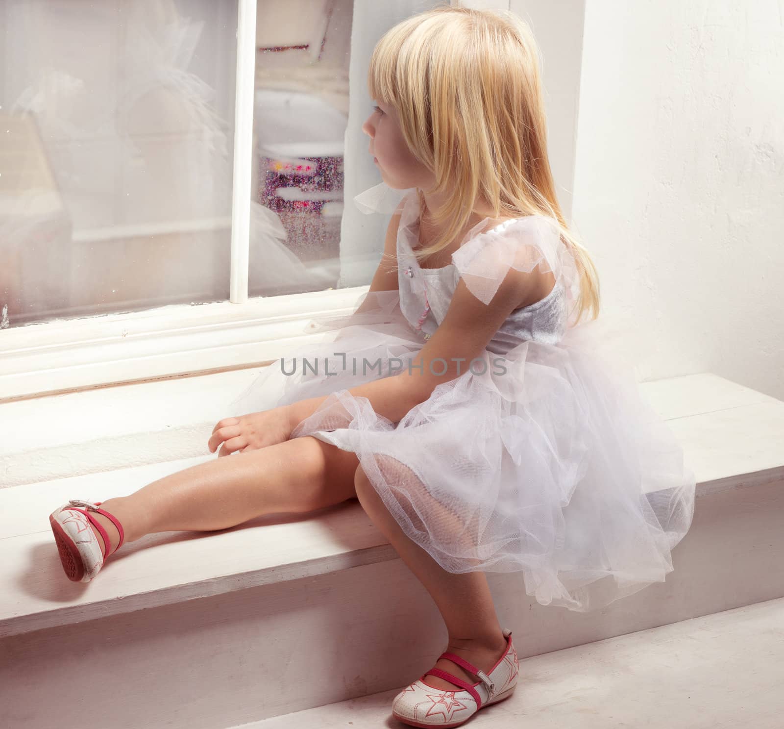 Girl 3 years old in a white dress near window by victosha