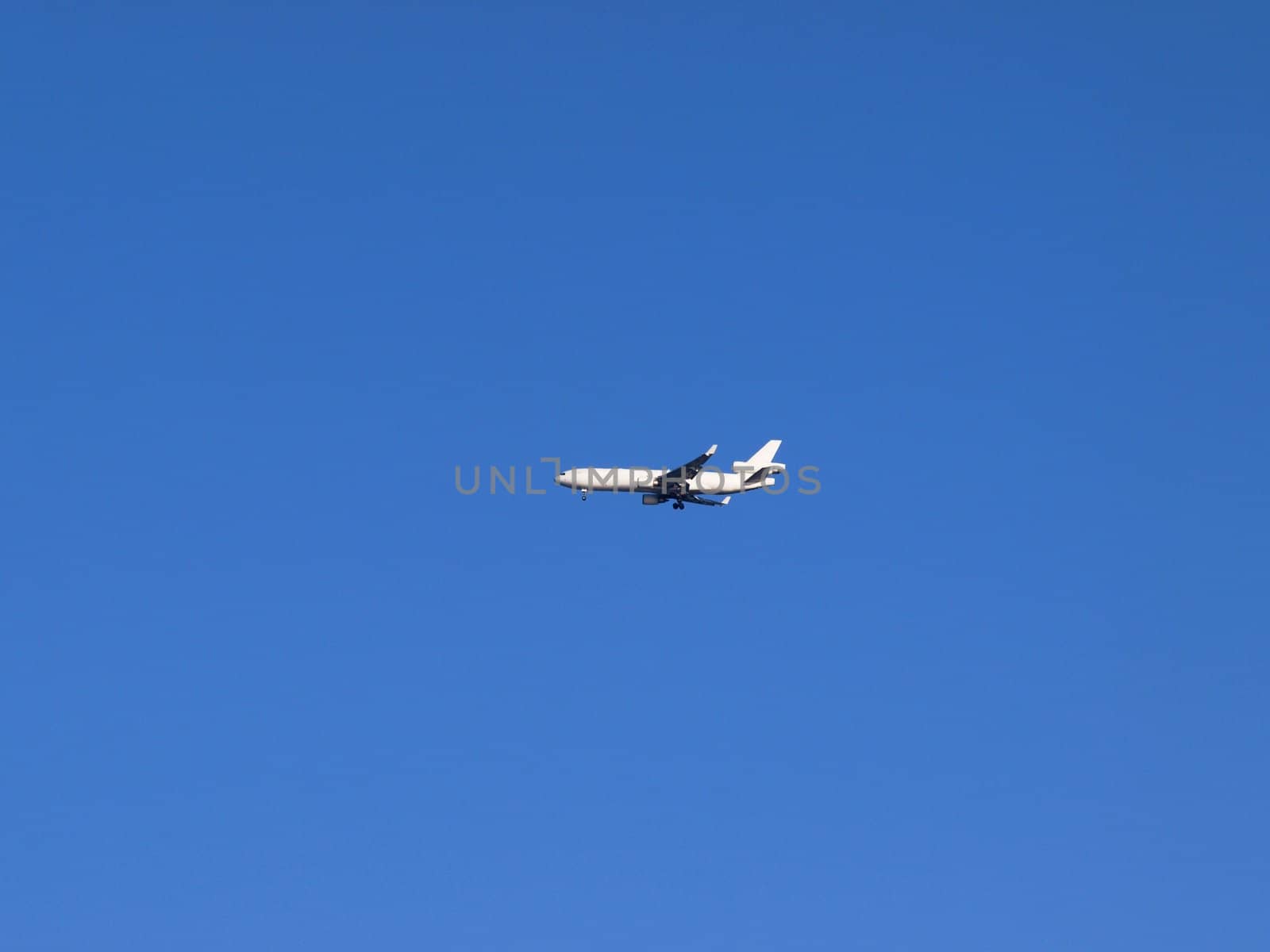 White airplane in the blue sky, coming in for landing